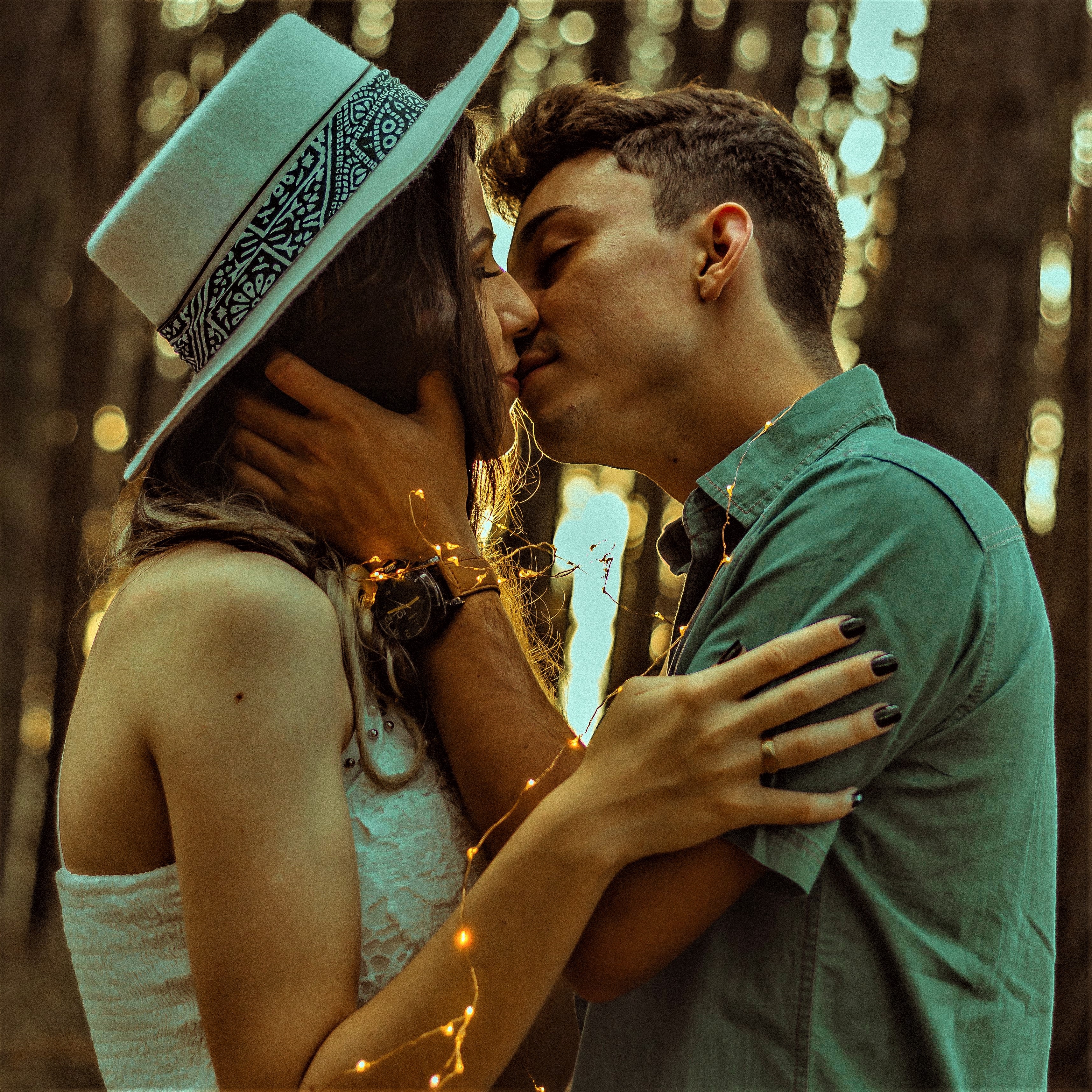 A couple kiss while holding a string of glowing fairy lights.